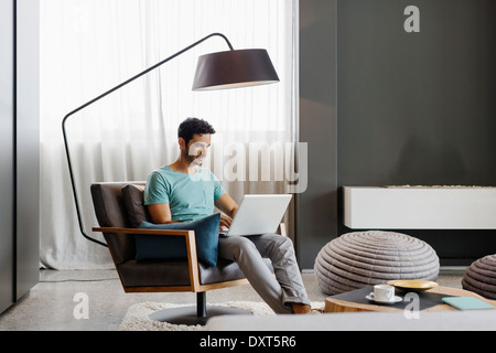 Mann mit Laptop im Wohnzimmer Stockfoto