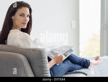 Porträt der selbstbewusste Frau auf Chaise Lounge Magazin lesen Stockfoto