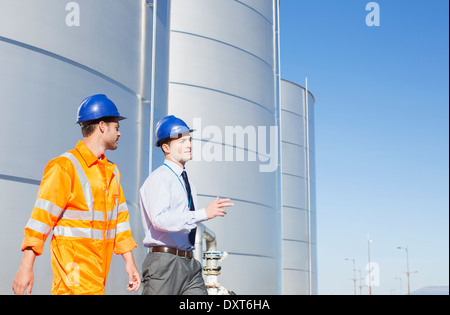 Unternehmer und Arbeitnehmer, die zu Fuß in der Nähe von Silage Speichertürme Stockfoto