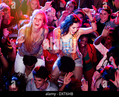 Männer tragen jubelnde Frauen auf Schultern in Menschenmenge beim Musikfestival Stockfoto