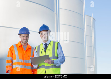 Porträt von Unternehmer und Arbeiter mit Klemmbrett in der Nähe von Silage Speichertürme Stockfoto