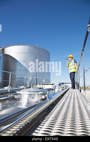 Arbeiter mit Walkie-talkie auf Plattform über Edelstahl noch Milch tanker Stockfoto