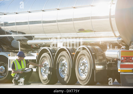 Arbeiter, die Überprüfung der Reifen auf Edelstahl Milch tanker Stockfoto