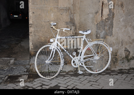 Ein Fahrrad weiß lackiert mit schwarzer Schrift an der Wand in Ortigia, Syrakus, Sizilien, Italien Stockfoto