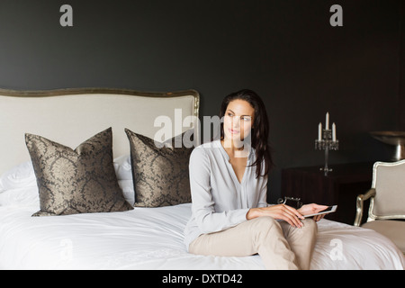 Fröhliche Frau, die mit digital-Tablette im Schlafzimmer Stockfoto
