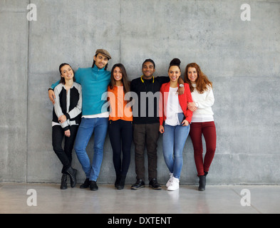 Gruppe von stilvollen jungen Studenten auf dem Campus. Multirassische junge Menschen zusammenstehen gegen die Wand in der Schule. Stockfoto