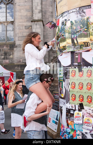 Performer hinzufügen ihre Plakate zu einem bereits überfüllten Wand. Stockfoto