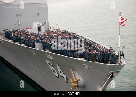 UNS Navy Matrosen an Bord der geführte Flugkörper Kreuzer USS Gettysburg Gruß während ein Befehl-Foto auf dem Vorschiff 10. März 2014 in den Golf von Oman. Gettysburg ist als Teil der Harry S. Truman Carrier Strike Group Unterstützung maritimer Sicherheitsoperationen und Sicherheitsbemühungen Zusammenarbeit Theater in den USA bereitgestellt 5. Flotte Aufgabengebiet. Stockfoto