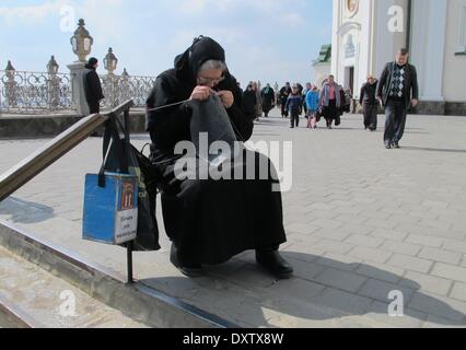 Potschajew, Ukraine. 28. März 2014. Eine alte Frau strickt und sammelt Spenden vor dem Heilige Dormition Potschajew Lawra Kloster Potschajew, Ukraine, 28. März 2014. Potschajew ist eines der fünf Russisch-orthodoxe Klöster der Ehrentitel "Lawra" für seine Bedeutung im Hinblick auf die Kirchenpolitik zu tragen. Foto: Friedemann Kohler/Dpa/Alamy Live News Stockfoto