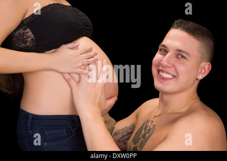 Lächelnden Vater mit seiner Frau schwangeren Bauch in den Händen Stockfoto