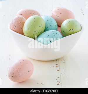 Gesprenkelte Ostereier in einer Vielzahl von Farben. In eine herzförmige Schüssel angeordnet. Stockfoto