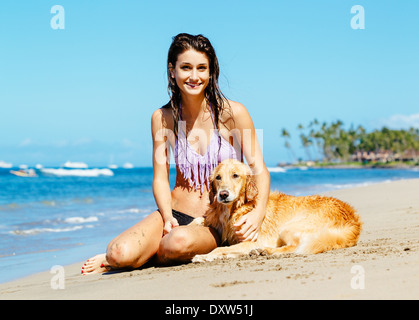 Attraktive junge Frau genießen sonnigen Tag am Strand mit ihrem Hund, Golden Retriever Stockfoto