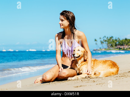 Attraktive junge Frau genießen sonnigen Tag am Strand mit ihrem Hund, Golden Retriever Stockfoto