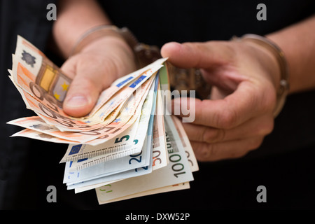 Mann in Handschellen hält Euro-Banknoten Stockfoto