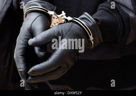 Nahaufnahme der Hände mit Handschuhen in Handschellen Stockfoto