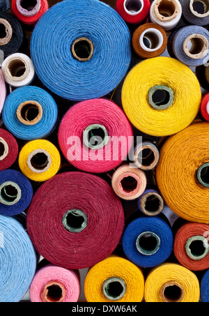 vertikale Nahaufnahme von Spulen des Threads von unterschiedlicher Größe, Textur und Farbe Stockfoto