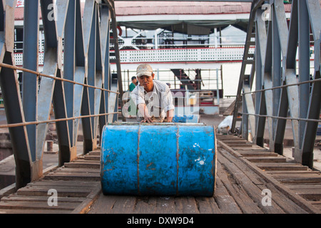 Schieben ein Fass leer Kraftstoff am Hafen in Yangon, Myanmar Stockfoto