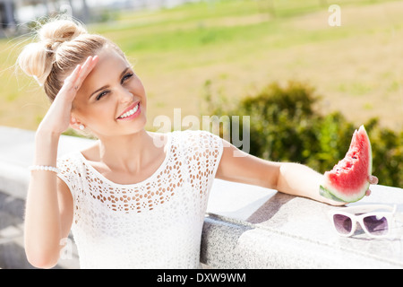 lächelndes Mädchen in weißen Sommerkleid hält ein Stück der süßen saftigen Wassermelone Stockfoto