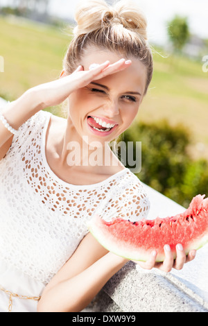 junges schönes Mädchen in weißen Spitzen Kleid hält ein Stück der süßen saftigen Wassermelone Stockfoto