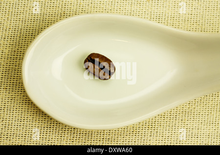 Frisch gerösteten Kaffee Körner Nahaufnahme in weißem Porzellanlöffel. Stockfoto
