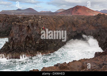 Touristen auf eine Aussichtsplattform mit Wellen, die in einem Meer Höhle im Felsen im Costa Los Hervideros Lanzarote Kanarische Inseln Stockfoto