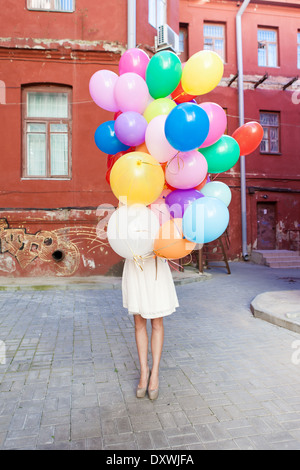 Mädchen in weißen Sommerkleid verbirgt sich hinter einem Haufen Luftballons Stockfoto