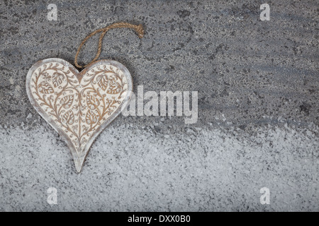 Herz auf grauem Kalkstein Hintergrund aus Holz geschnitzt Stockfoto