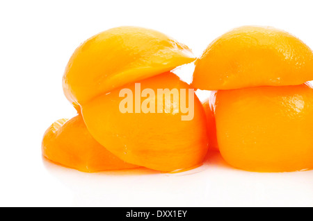 einige geschälte und halbierte Pfirsiche in Sirup auf weißem Hintergrund Stockfoto