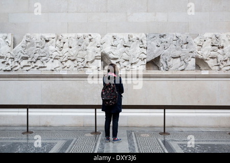 Ein Tourist schaut auf einen Abschnitt von einem Fries aus der Parthenon-Skulpturen, British Museum, London. Stockfoto