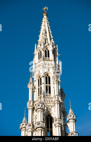 Hoch aufragenden 96 m (315 ft) über das Kopfsteinpflaster am Grand Place, der Turm des reich verzierten Brüssel Rathaus (Hotel de Ville) ist von einer Statue des Heiligen Michael slaying einen Drachen, eine historische Wahrzeichen der Stadt begrenzt. Grand-Place (La Grand-Place) ist ein UNESCO-Weltkulturerbe in zentrale Brüssel, Belgien. Kunstvollen, historischen Gebäuden gesäumt, ist der gepflasterten Platz die wichtigste touristische Attraktion in Brüssel. Stockfoto