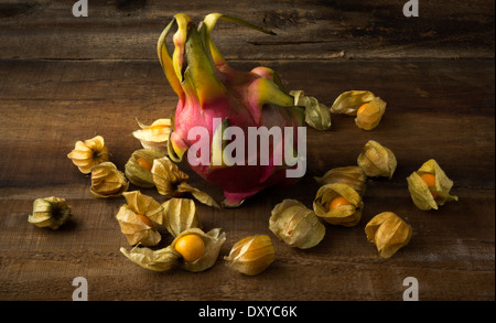 Ganze Drachenfrucht auf Holzbrett umgeben von Stachelbeeren Stockfoto