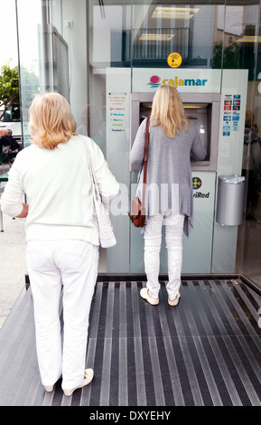 Zwei Frauen mit einem Cajamar Bank ATM Geldautomat, Turre, Almeria, Andalusien Spanien Europa Stockfoto