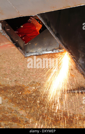 Funken fliegen als Stahl, aus einem alten Lastkahn durch eine Sauerstoff Acetylen-Taschenlampe auf einer Werft in Malaysia geschnitten. Stockfoto