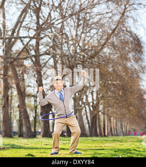Senior woman ein Hula Hoop Übung und gestikulierte Glück im park Stockfoto