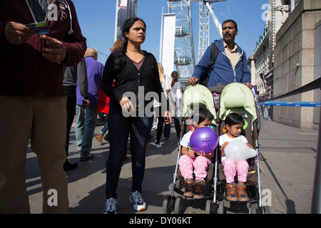 Touristen drängen Zwillinge in einem Kinderwagen in der Nähe des London Eye, zieht eines der größten für den Tourismus nach unten am Südufer. London, UK Stockfoto