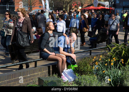 Frau, genießen Sie die Sonne in ihrer eigenen ruhigen Welt verloren, da die Massen von Menschen an einem Frühlingstag entlang. South Bank, London, UK. Stockfoto