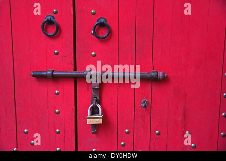 Rote Tür mit schwarzen Schmiedearbeiten und Vorhängeschloss Stockfoto