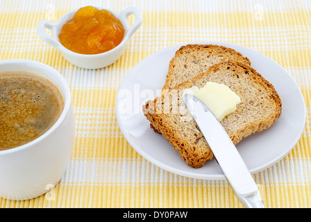 Frühstück mit Toast mit Butter und Marmelade und Kaffee auf gelbe Platzdeckchen Stockfoto