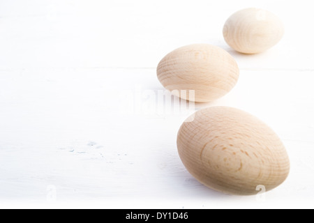 Drei Holz Eiern von vorne nach hinten auf der einen Seite des Fotos angeordnet. Die hölzernen Eiern sind in natürlichem Licht und Farbe. Stockfoto