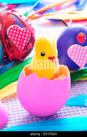 eine Teddy-Küken aus einer schraffierten rosa Ei und einige Ostereier bemalt in verschiedenen Farben und Mustern Stockfoto