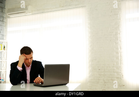 Zuversichtlich Geschäftsmann sitzt am Tisch mit Laptop im Büro Stockfoto