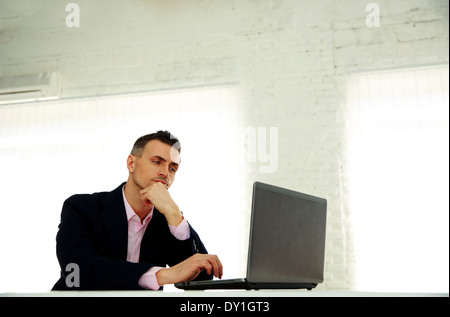 gut aussehend Geschäftsmann arbeiten auf einem Laptop im Büro Stockfoto