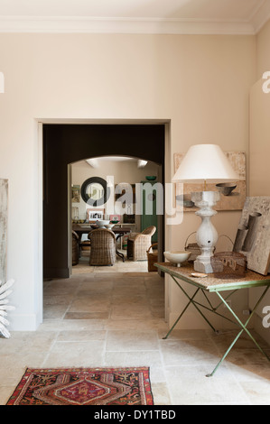 Blick vom Salon durch Dining room mit Steinböden. Eine steinerne Lampe sitzt auf einem schmiedeeisernen Klapptisch in der Ecke Stockfoto