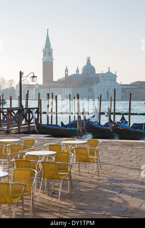 Venedig - Stühle am Markusplatz und San Giorgio Maggiore Kirche im Hintergrund im Morgenlicht. Stockfoto