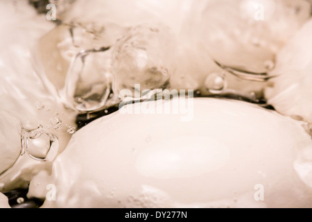 Luftblasen an der Oberfläche des kochenden Wassers, wie vier weißen Eiern in einem Topf gekocht werden Stockfoto