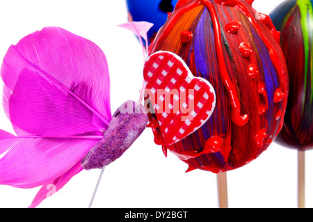 ein Haufen von Ostereiern lackiert in verschiedenen Farben und Mustern und ein rosa Schmetterling auf einem weißen Hintergrund Stockfoto