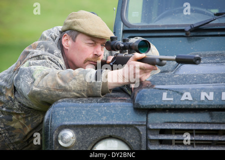 Ein Spiel-Keeper Schädlinge im Laufe des Tages von einem Land Rover Fahrzeug mit einem Gewehr schießen Stockfoto