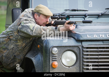 Ein Spiel-Keeper Schädlinge im Laufe des Tages von einem Land Rover Fahrzeug mit einem Gewehr schießen Stockfoto