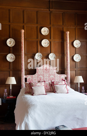 Toile De Jouy Bett Dressings von Designarchiv in Schlafzimmer mit hölzernen Wandverkleidungen und dekorativer Porzellanteller Stockfoto