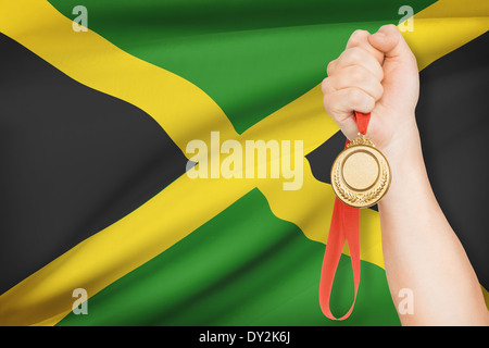 Sportler halten Goldmedaille mit Flagge auf Hintergrund - Jamaika Stockfoto